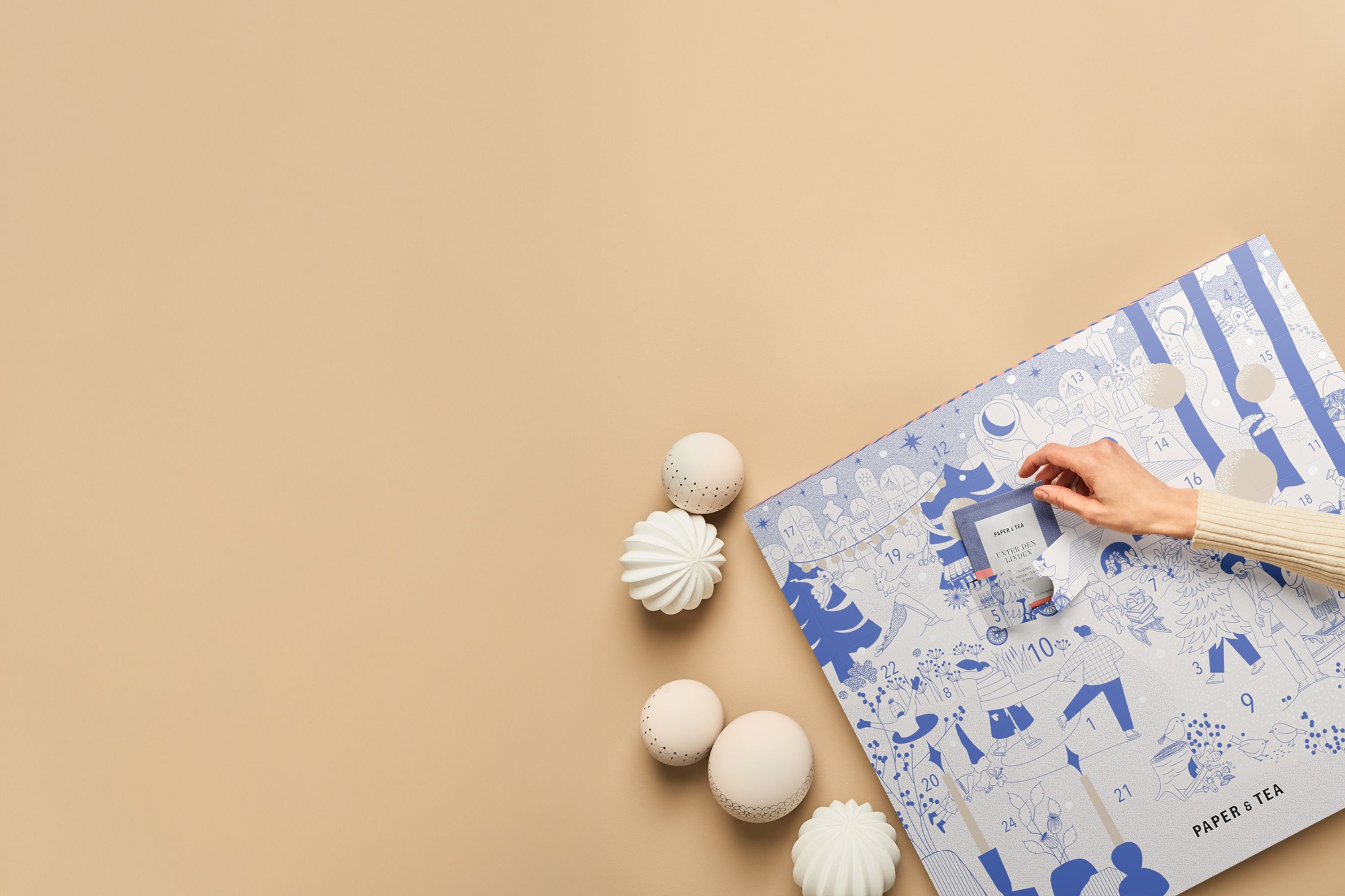 Festlicher Adventskalender von Paper & Tea, Türchen 19 geöffnet, zeigt Bio-Kräutertee 'Unter den Linden', dekoriert mit weißen Kugeln.