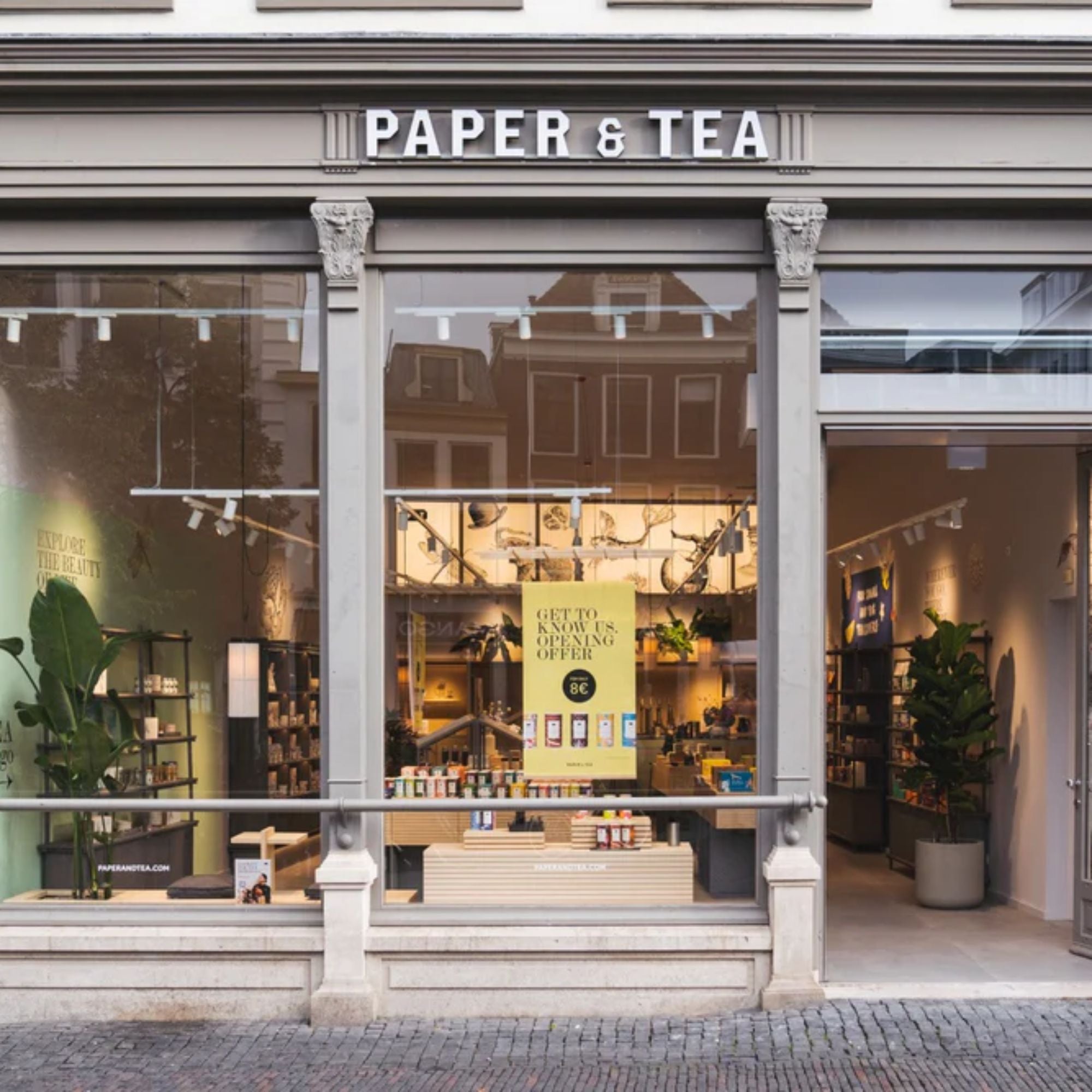 Ladenfront von PAPER & TEA mit beleuchtetem Innenraum und gelbem Eröffnungsangebotsschild für 8 €