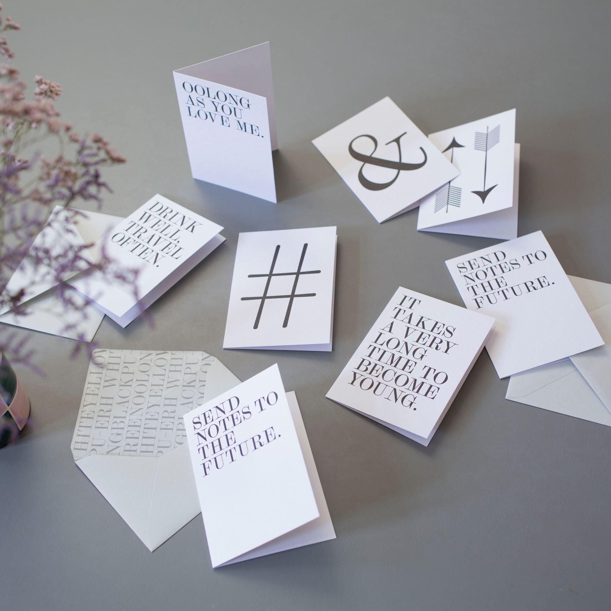 Weiße Karten mit inspirierenden Texten 'OOLONG AS YOU LOVE ME' und 'SEND NOTES TO THE FUTURE', grauer Hintergrund