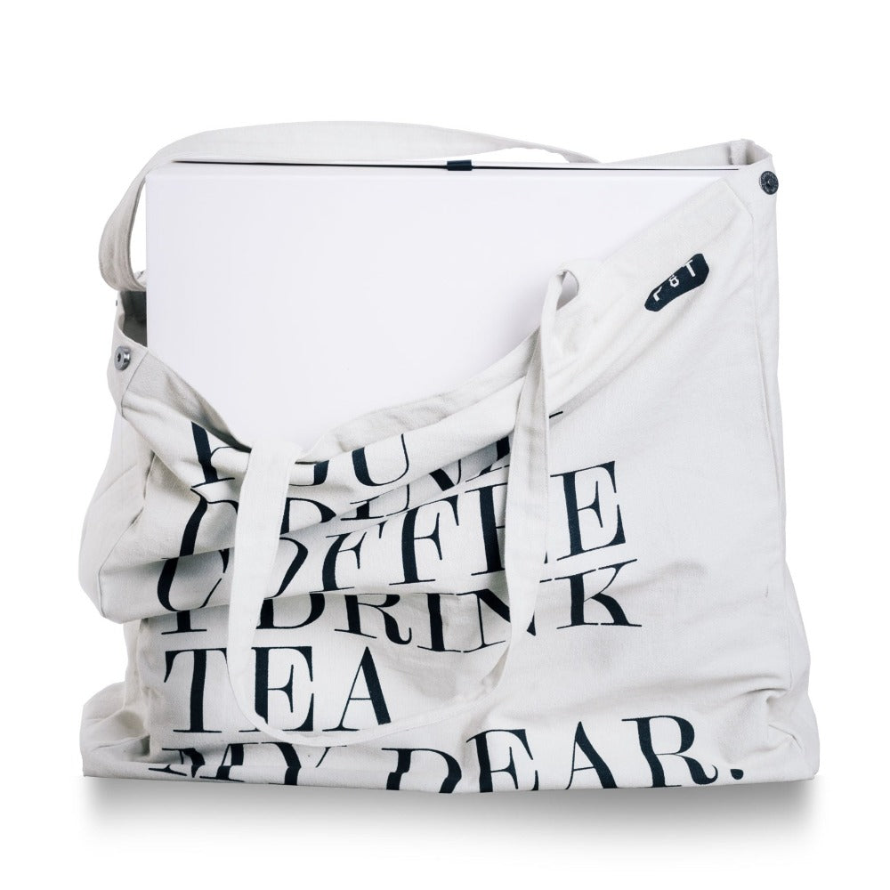 Weiße Canvas-Tragetasche mit schwarzem Aufdruck 'DRINK TEA DEAR' und P & T Logo, teilweise sichtbarer Laptop.