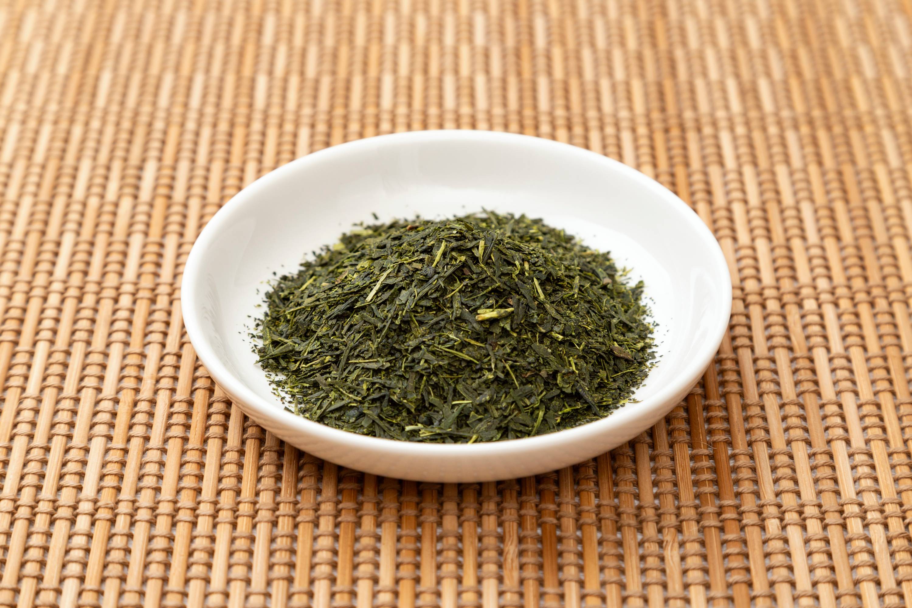 Schale mit losem Grüntee auf hellbrauner Unterlage