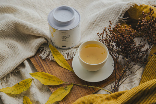 Teedose mit gelbem Tee neben einer gefüllten Tasse Tee