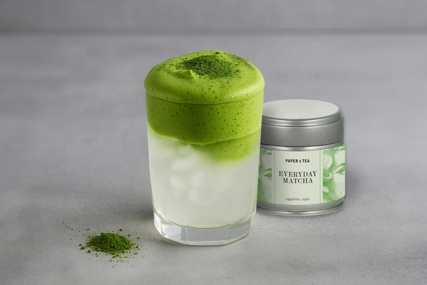Glas mit eisgekühltem, geschichtetem Matcha und Kokosnusswasser, daneben Metalldose und Matcha-Pulver aus Kagoshima