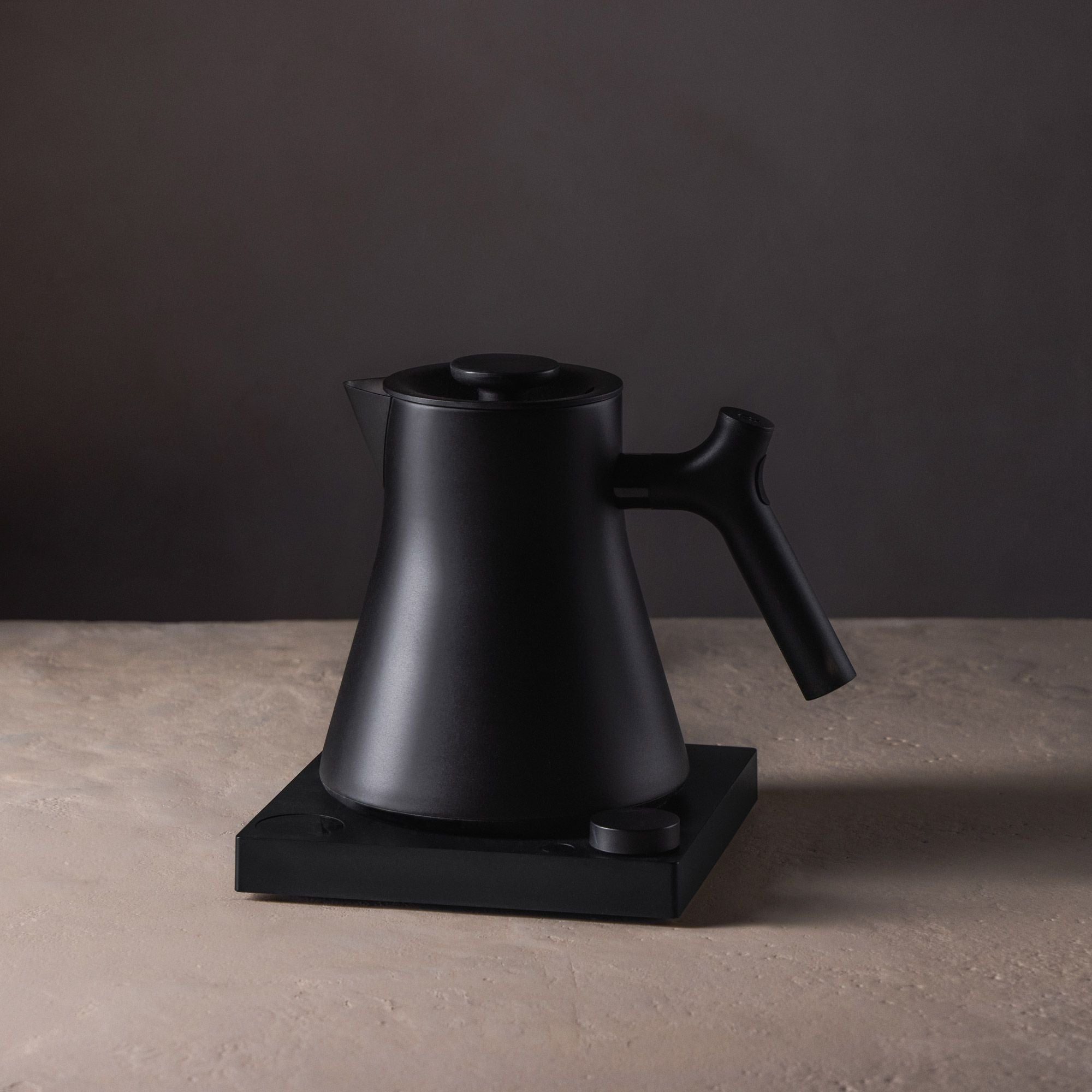 Moderner, mattschwarzer Wasserkocher mit ergonomischem Griff auf quadratischer Basis.