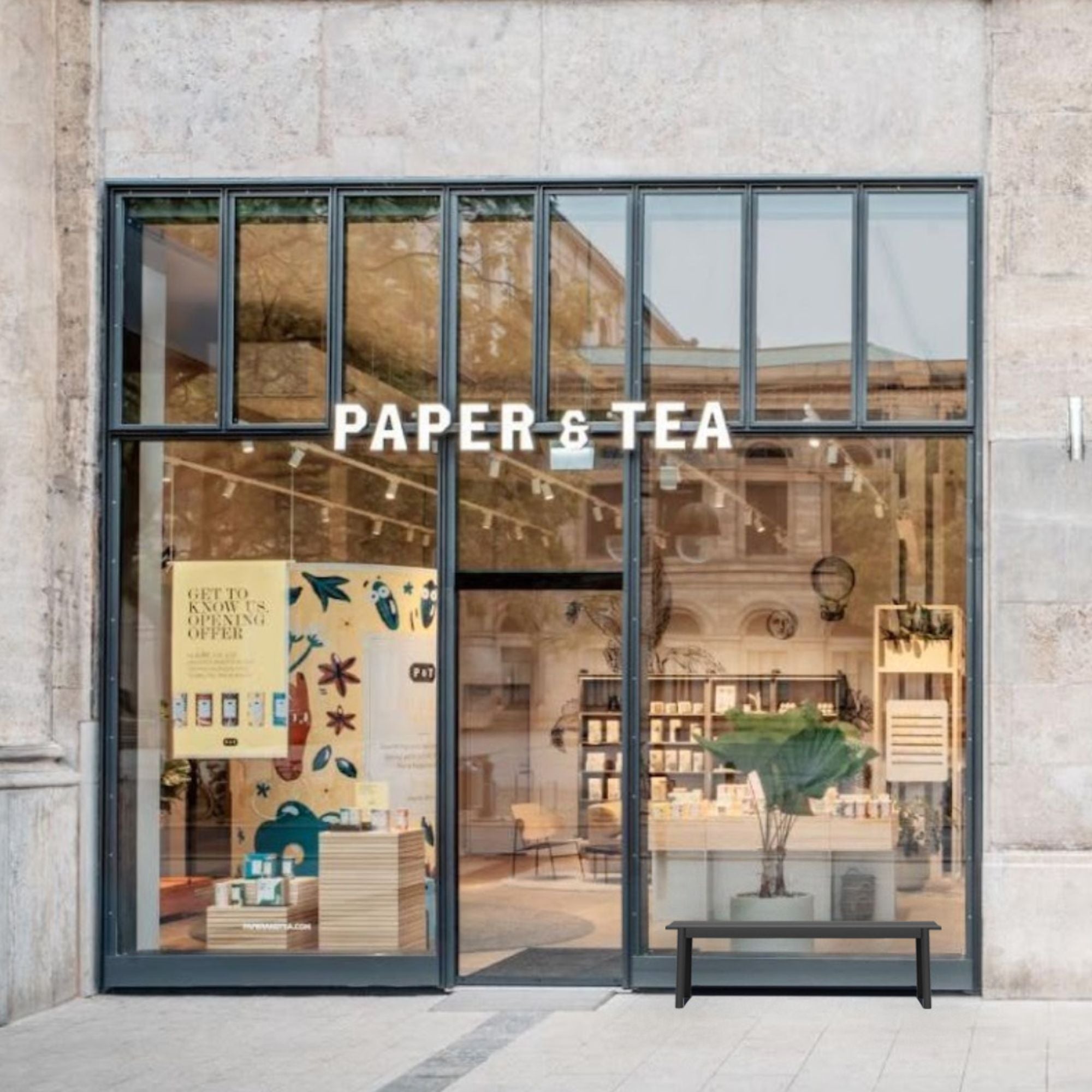 Modernes Teegeschäft PAPER & TEA mit großen Glasfenstern und gelbem Angebotsschild.