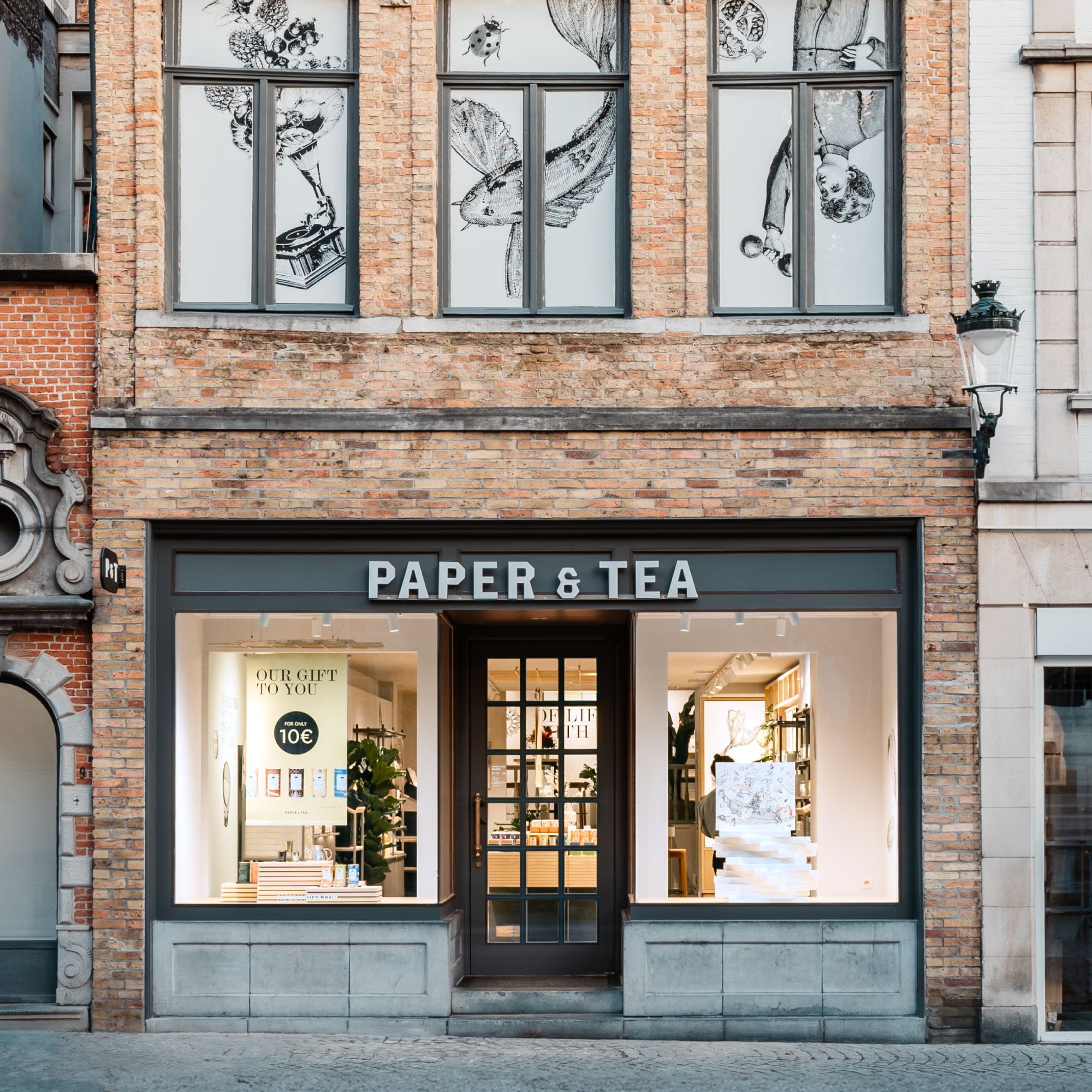 Stilvoller PAPER & TEA Laden mit Glasfront, Geschenkangebot für 10 €, Pflanzen, Vintage-Illustrationen.