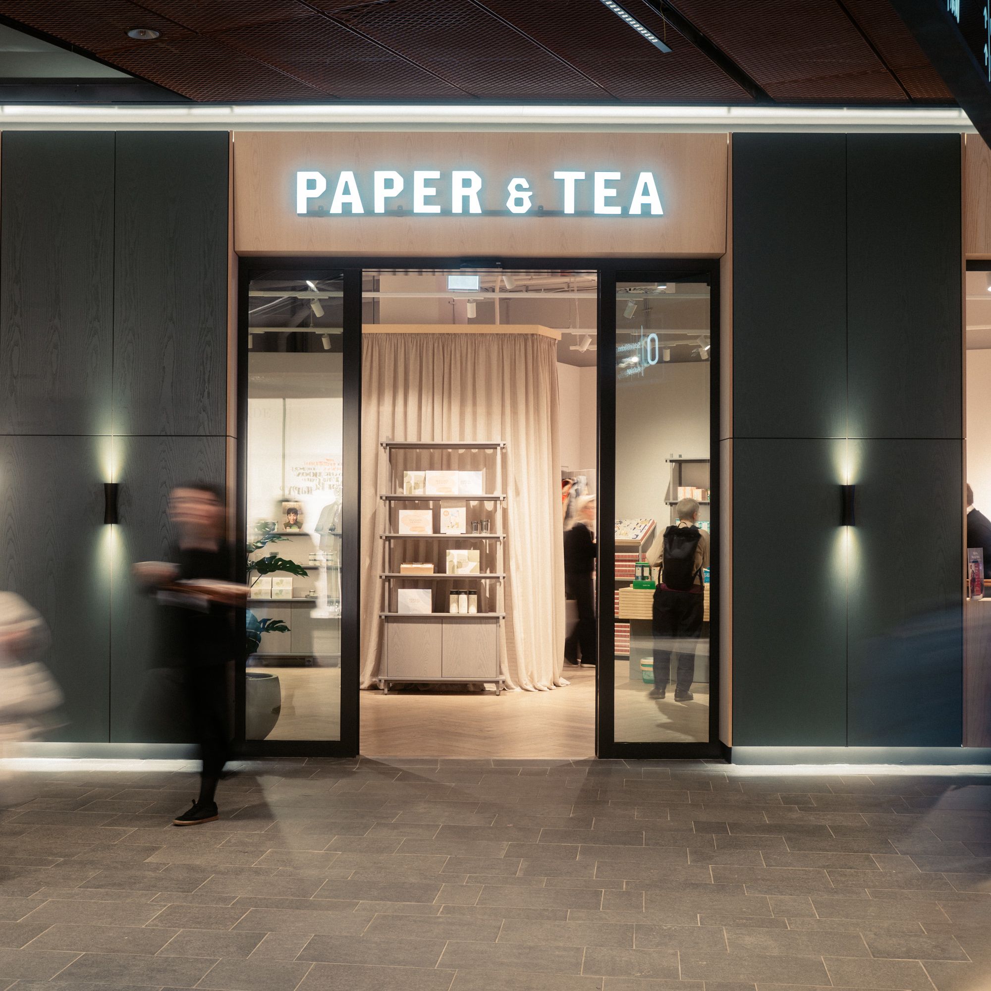 Moderner Laden mit Holzrahmen und Glasflügeltüren, Regale mit Papier- und Teeprodukten bei PAPER & TEA.