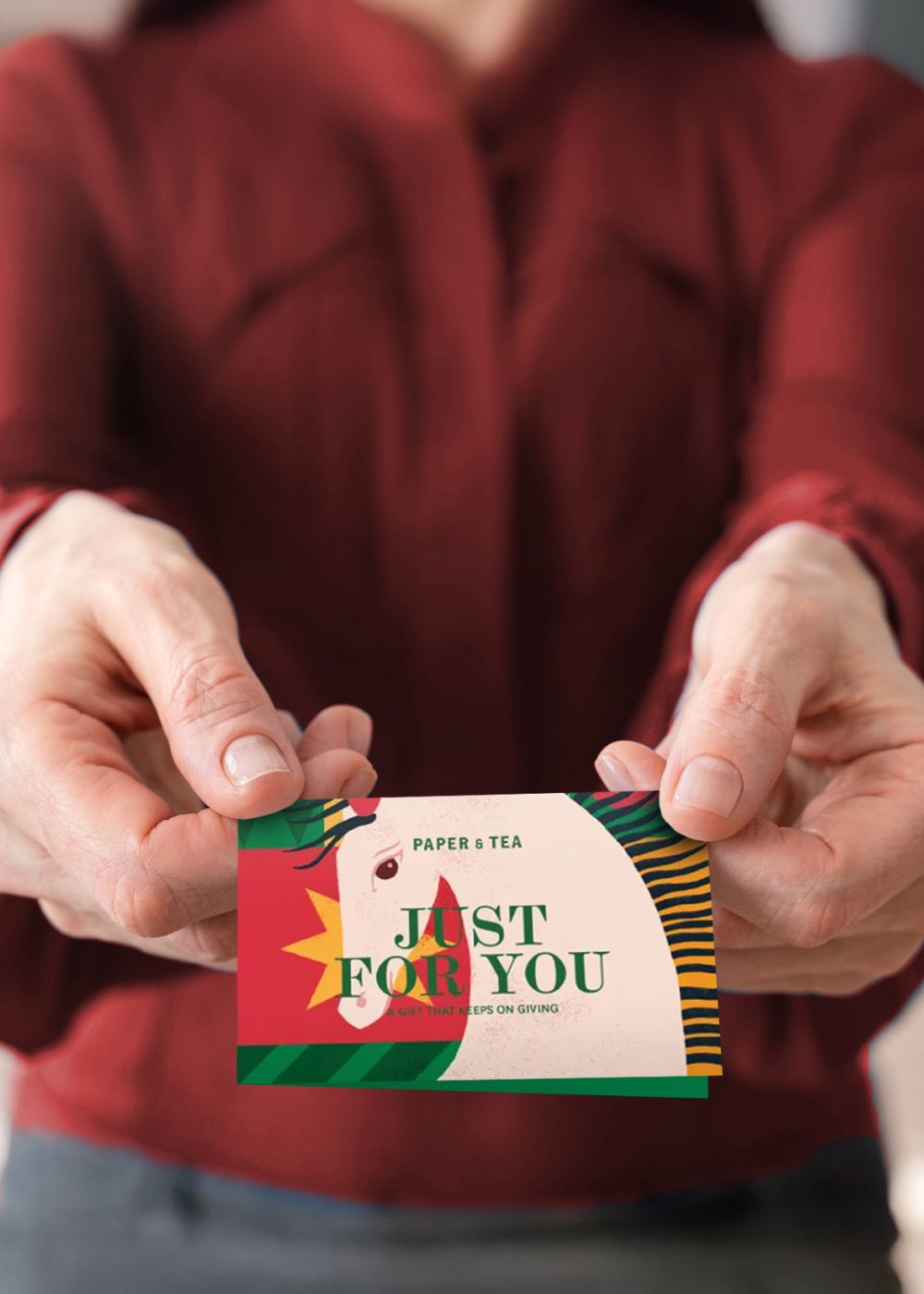 Person in rotem Langarmshirt hält bunte PAPER & TEA Geschenkkarte mit Pferdekopf und Aufschrift "JUST FOR YOU".
