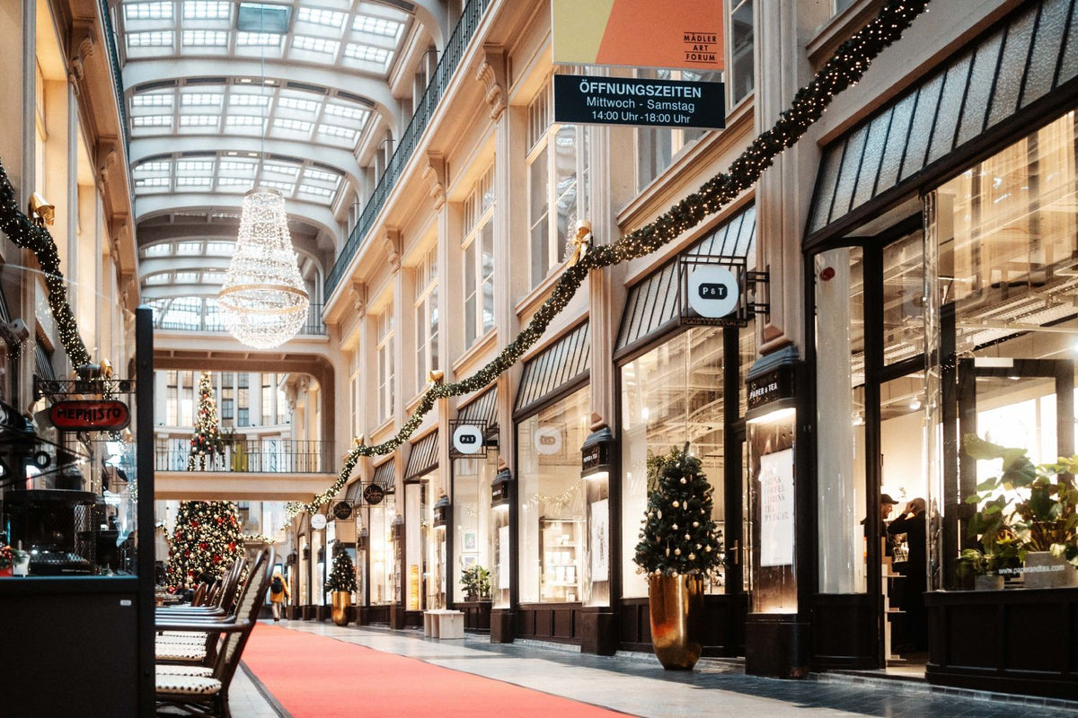 Elegante Einkaufsarkade mit Glasdach, rotem Teppich, Weihnachtsdekorationen und P&T Teegeschäft.