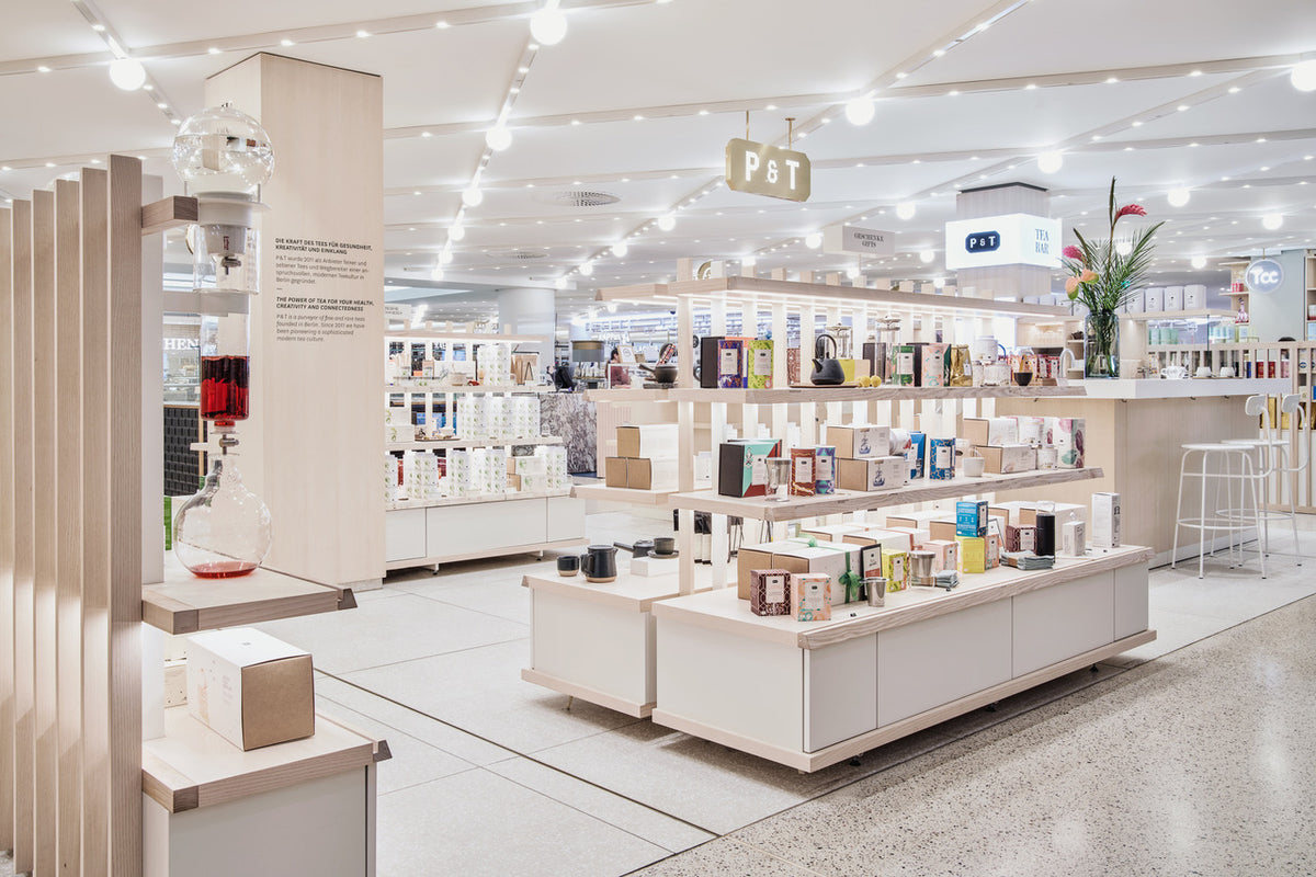 Moderne Verkaufsausstellung mit beleuchteten P & T Schildern und vertikalem Glas-Teezubereiter.